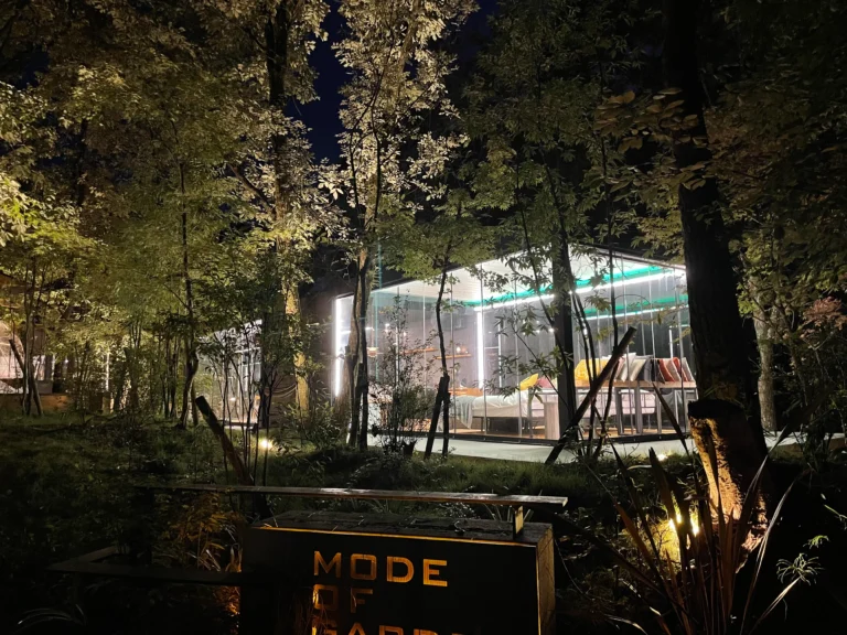 Exterior night view of Hikari no Hako, a fully glass-walled villa nestled in the forest at COMOREBI Yufuin glamping resort.