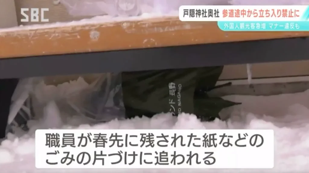 Trash bags left under a bench at Togakushi Shrine, showing the litter problem that shrine staff must clean up each spring.