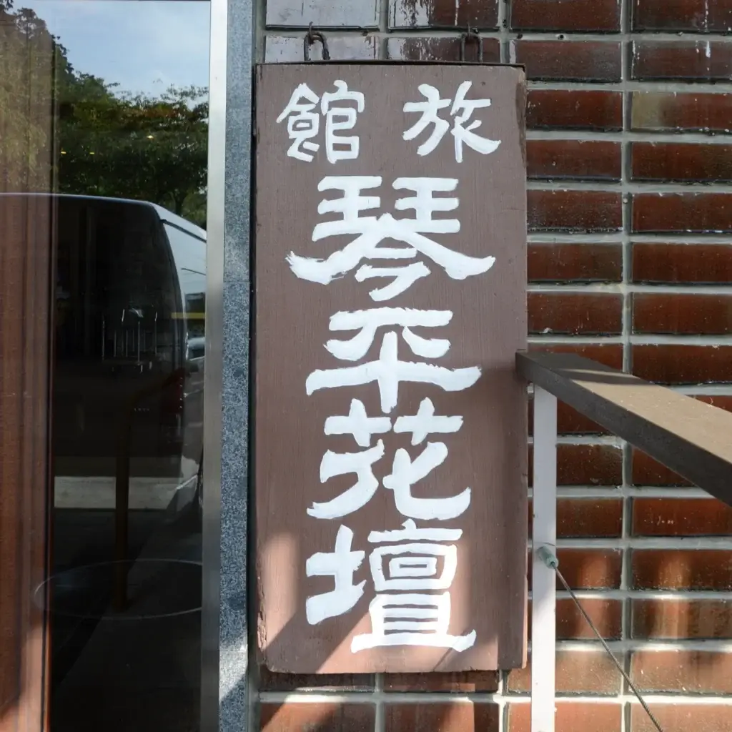 The lounge at Kotohira Kadan ryokan in Kagawa, featuring a modern wooden ceiling design and panoramic windows overlooking the Japanese garden where guests can enjoy a welcome drink.