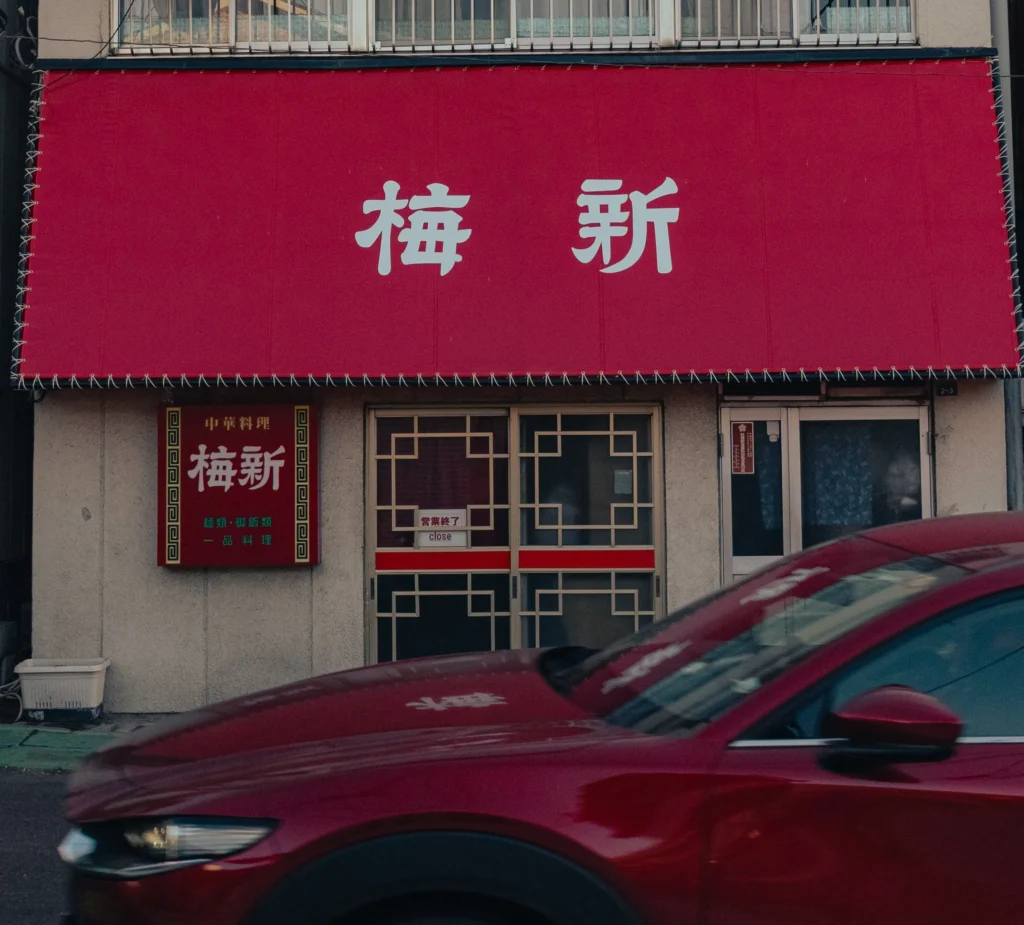 The bright red sign of a classic Chinese restaurant named 'Baishin' in the Nishiura Fujiyoshida district.