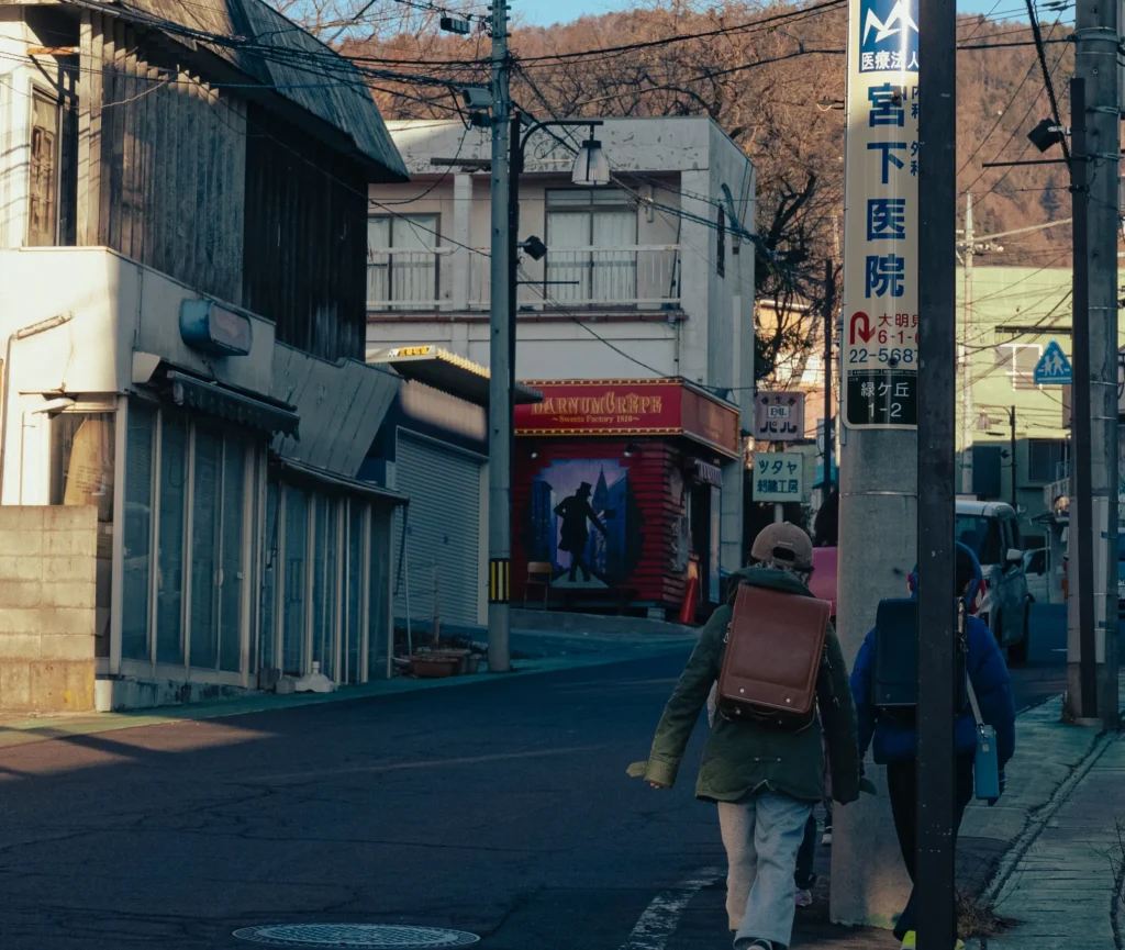 Schoolchildren with randoseru backpacks walking down a street in the Gekkeiji area of Nishiura, Fujiyoshida.