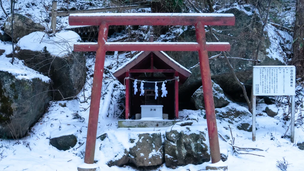 The Haha no Shirataki Shrine, an auxiliary shrine of Kawaguchi Asama Shrine, with its red torii gate standing in the snow.