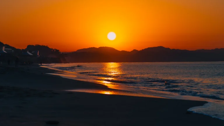 Sunrise over Shichirigahama Beach in Kamakura, with golden light reflecting on the sea and the silhouette of Enoshima