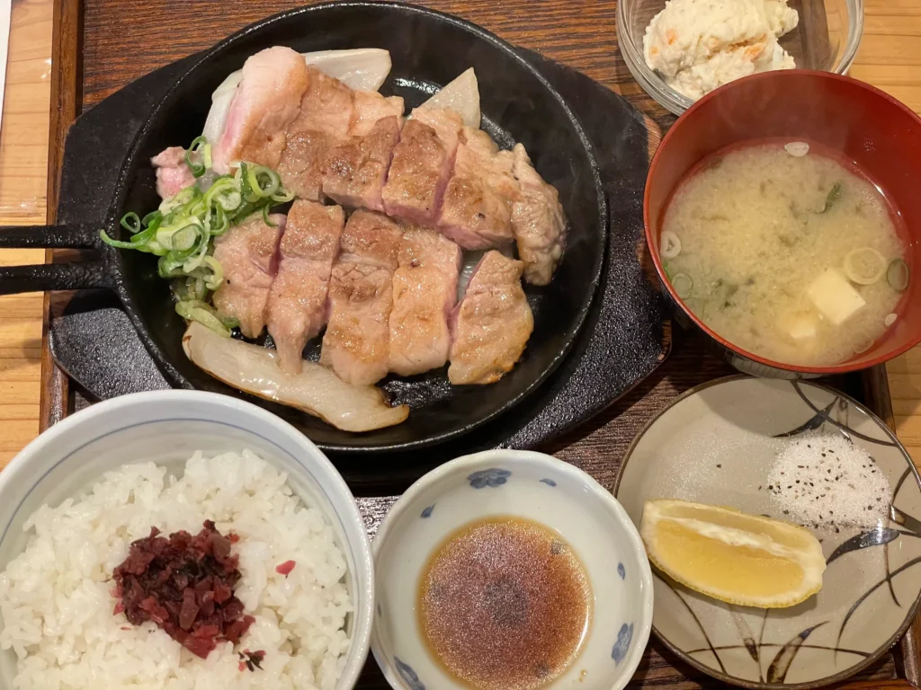The complete Toichi pork steak set, featuring sizzling teppan-grilled pork, rice, miso soup, and condiments.