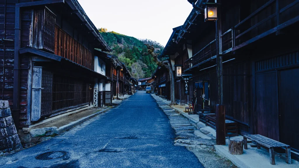 Traditional wooden buildings with lattice windows (tateshige-goshi) lining the stone-paved main street of Tsumago-juku, a preserved Edo-period post town on the Nakasendo trail in Nagano Prefecture.