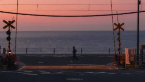The famous Slam Dunk crossing in Kamakura at sunrise, with the Enoden railway tracks leading towards the sparkling Shonan coast.
