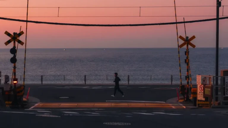 The famous Slam Dunk crossing in Kamakura at sunrise, with the Enoden railway tracks leading towards the sparkling Shonan coast.