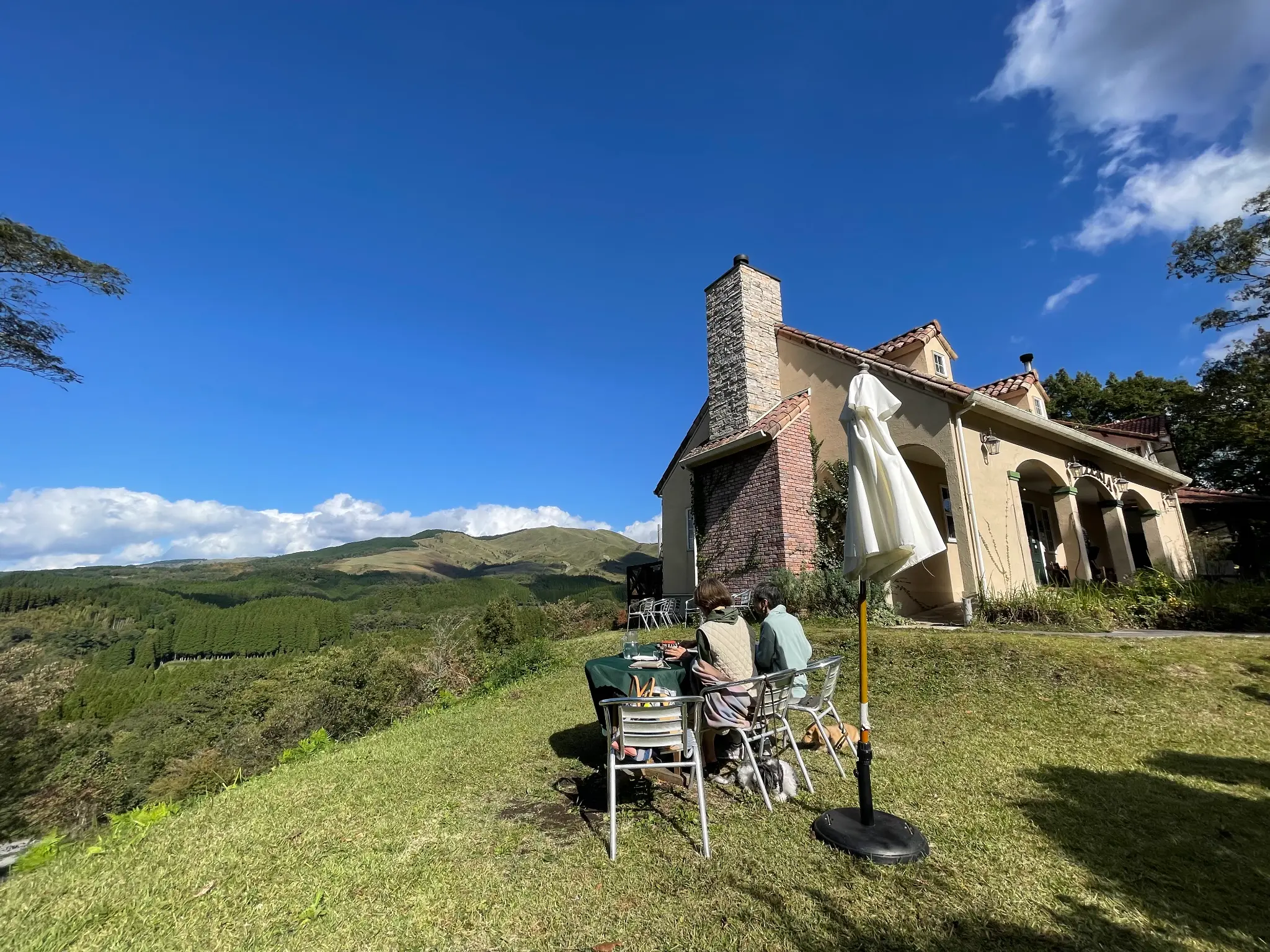 The scenic view from Pizzeria Tre Passo near Kurokawa Onsen, showing the restaurant's terrace overlooking the Aso mountains.