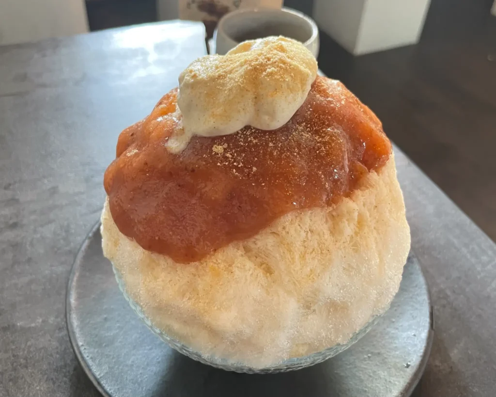 A generous serving of Peach and Chai kakigori, topped with a dollop of spiced cream.