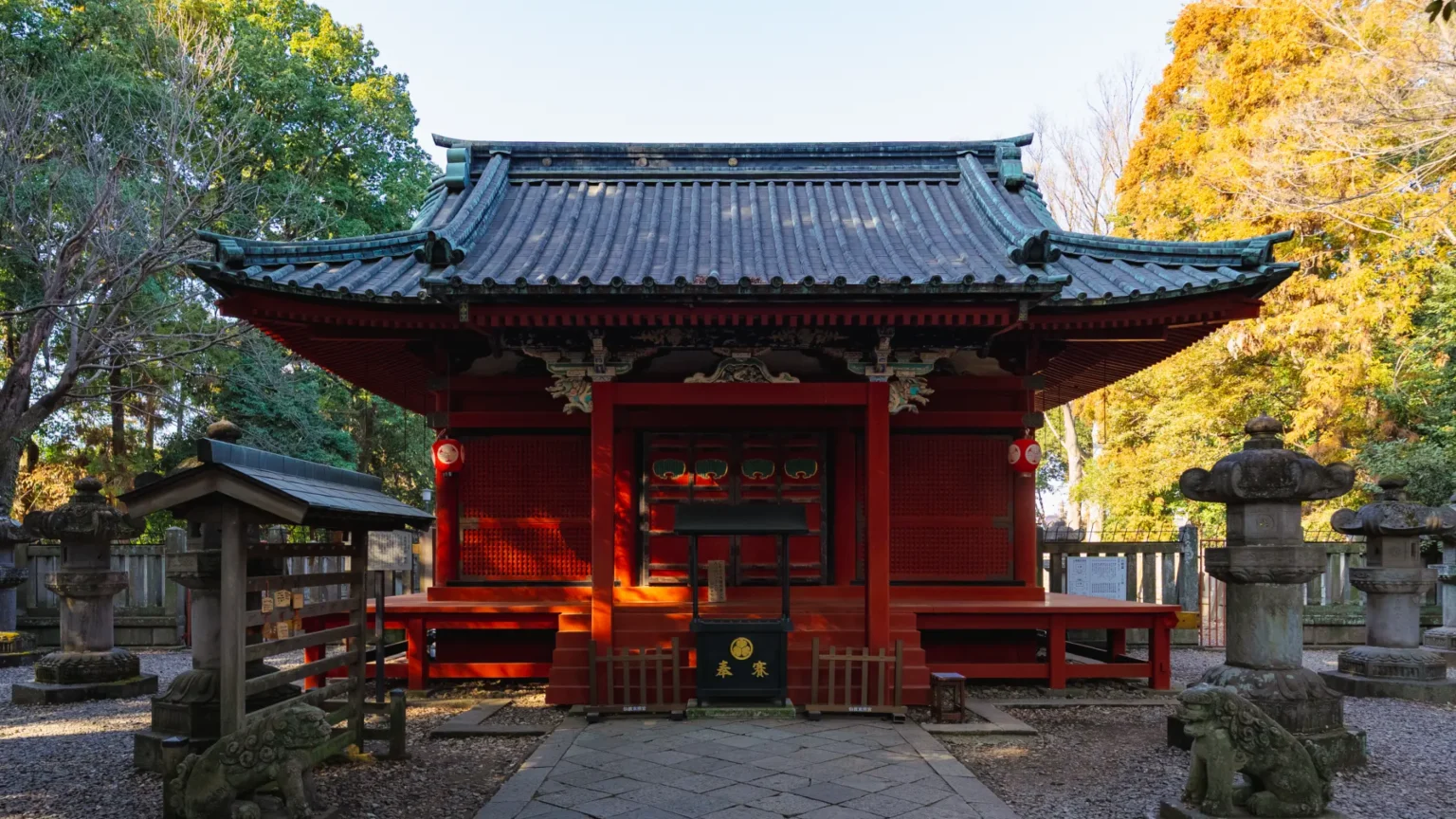 The main hall (haiden) of Senba Toshogu, a brilliant vermilion structure surrounded by stone lanterns and autumn trees.
