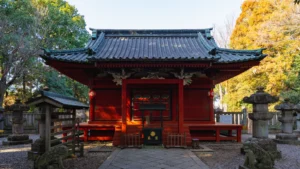 The main hall (haiden) of Senba Toshogu, a brilliant vermilion structure surrounded by stone lanterns and autumn trees.