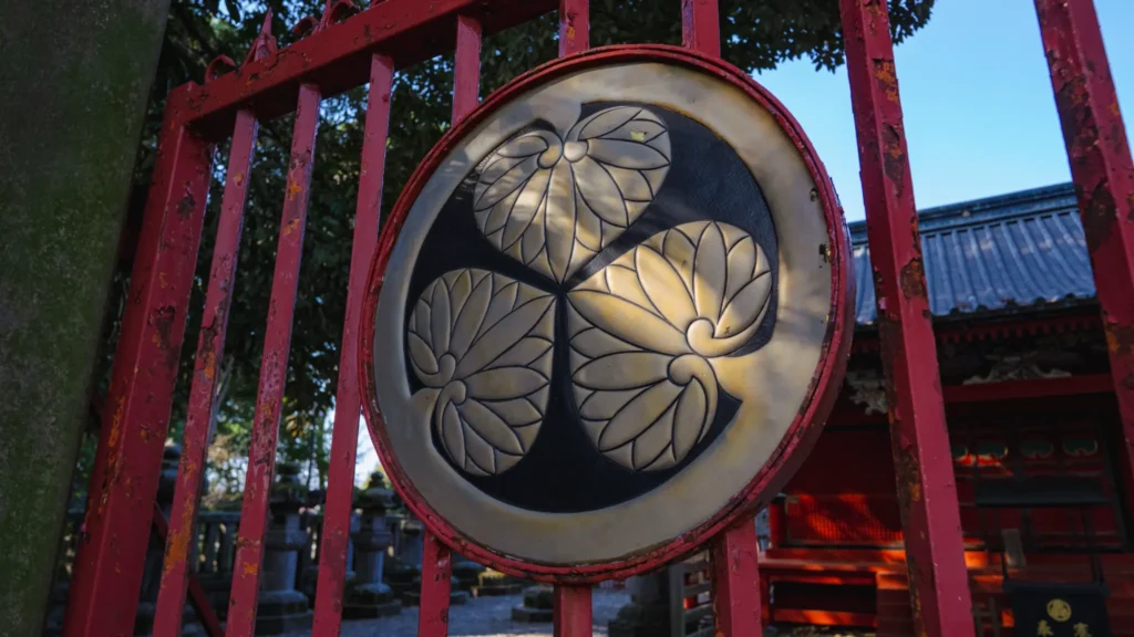 A close-up of the Tokugawa family crest, the Mitsuba Aoi, on the red gate of Senba Toshogu.