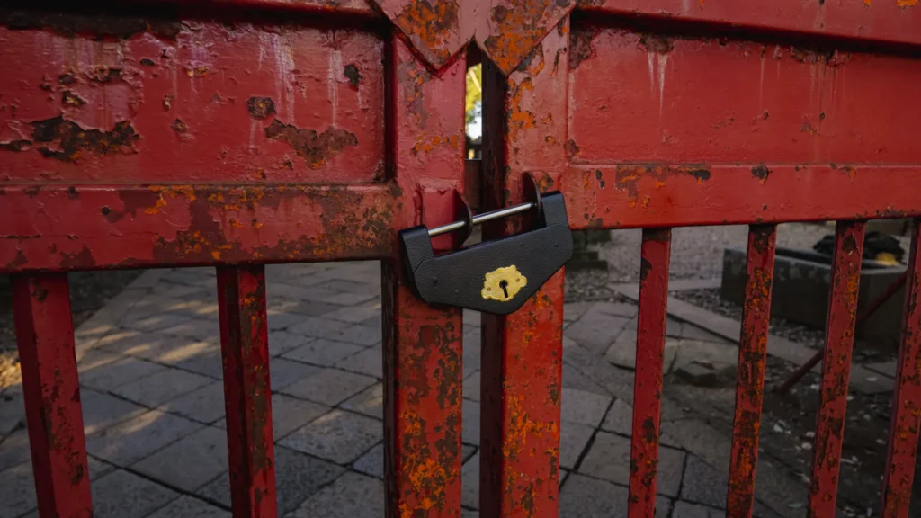 The locked red iron gate in front of the main hall, symbolizing the shrine's protected status.