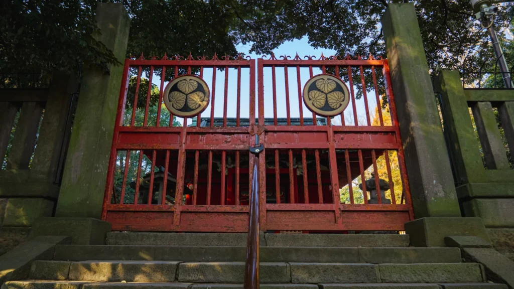 The red iron gate with two Tokugawa crests, seen from the bottom of the stone steps.