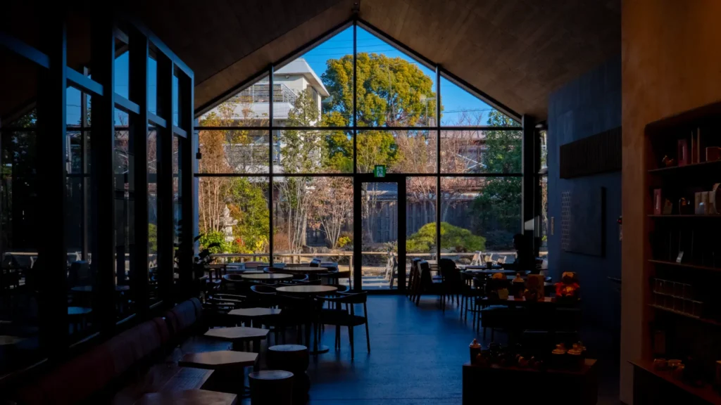 The spacious interior features a high ceiling and a large triangular window offering a view of the serene Japanese garden.