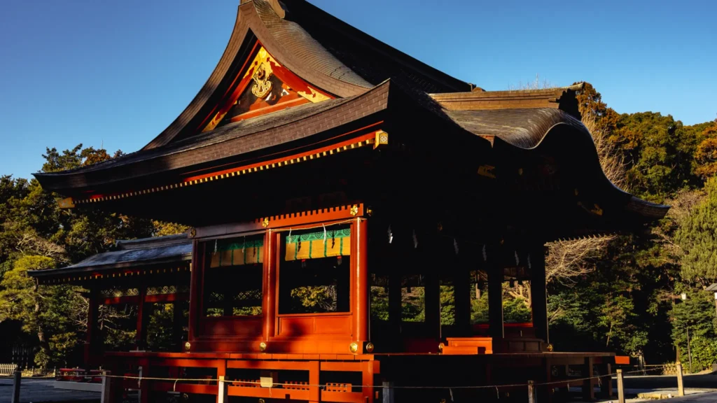The vermilion-lacquered Maiden dance stage, with its elegant curved roof, set against the backdrop of the shrine's trees.