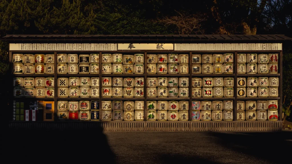 A wall of decorative sake barrels (kazaridaru) offered to the shrine, illuminated by the morning sun.