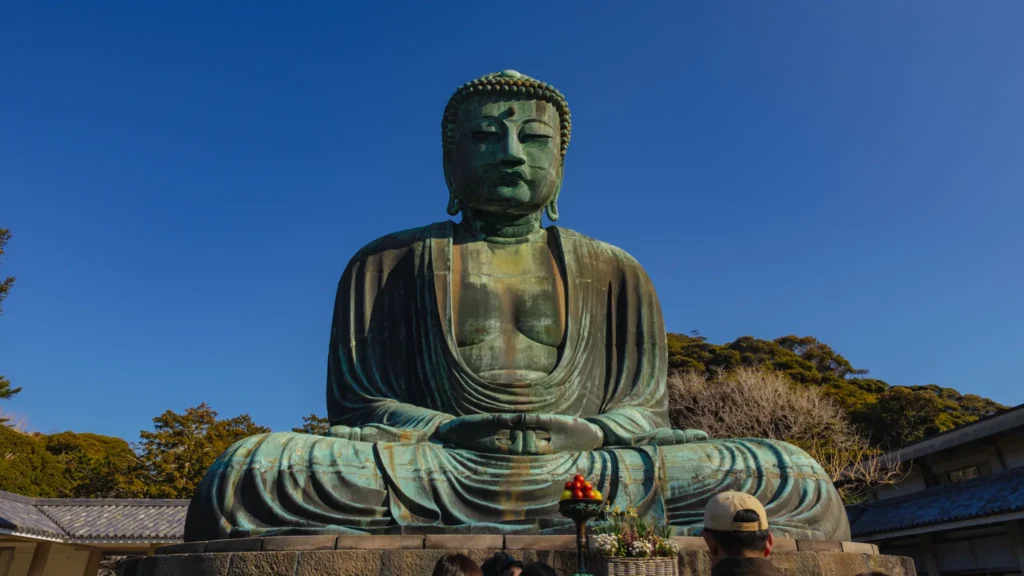 A frontal close-up shot of the Great Buddha of Kamakura against a clear blue sky.