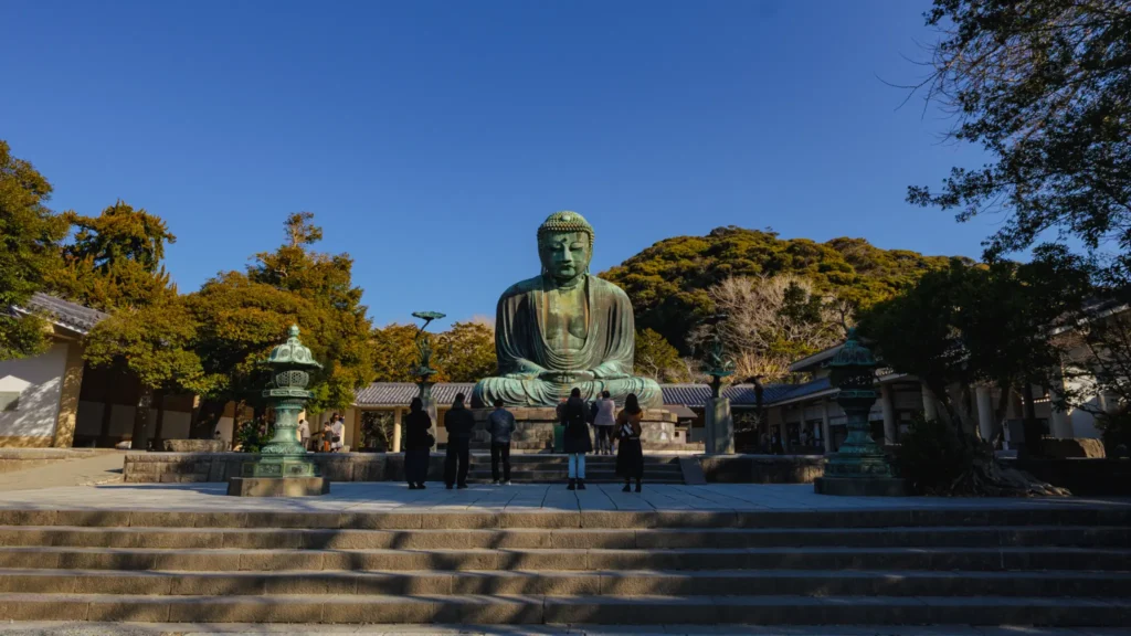 A view of the Great Buddha from the base of the stone steps, with visitors admiring the statue.