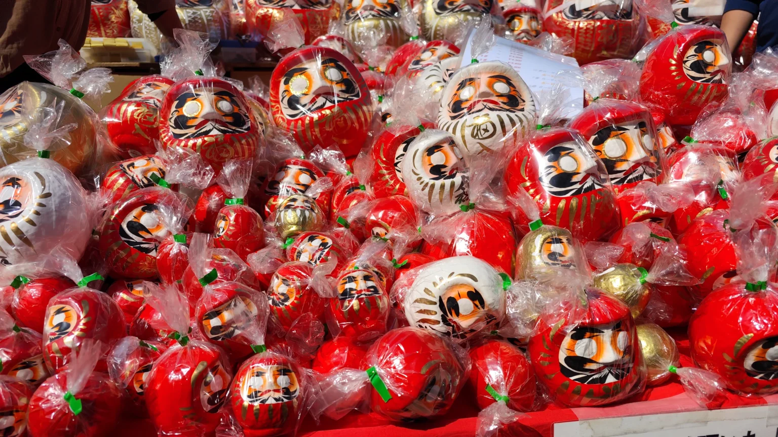 A vibrant stall at the Jindaiji Daruma Ichi, overflowing with red and white daruma dolls ready for purchase.