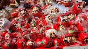 A vibrant stall at the Jindaiji Daruma Ichi, overflowing with red and white daruma dolls ready for purchase.