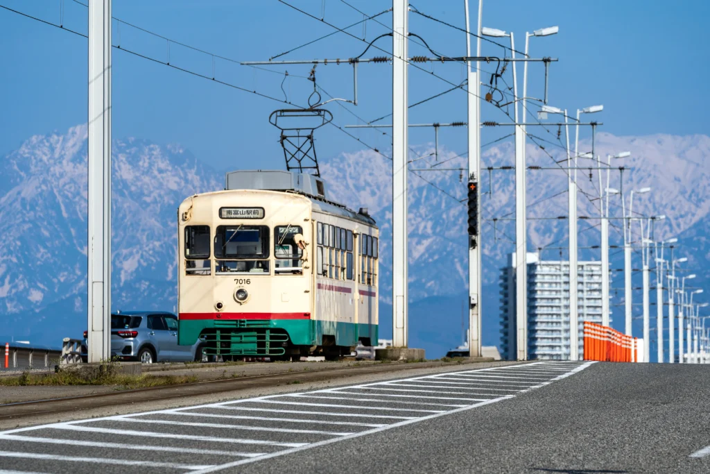 A vintage tram in Toyama with the snow-capped Tateyama mountains in the background