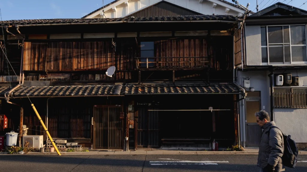 A historic street in the Fushimi district of Kyoto, with traditional wooden buildings and a sake shop sign, embodying the Fushimi walking guide Kyoto experience.