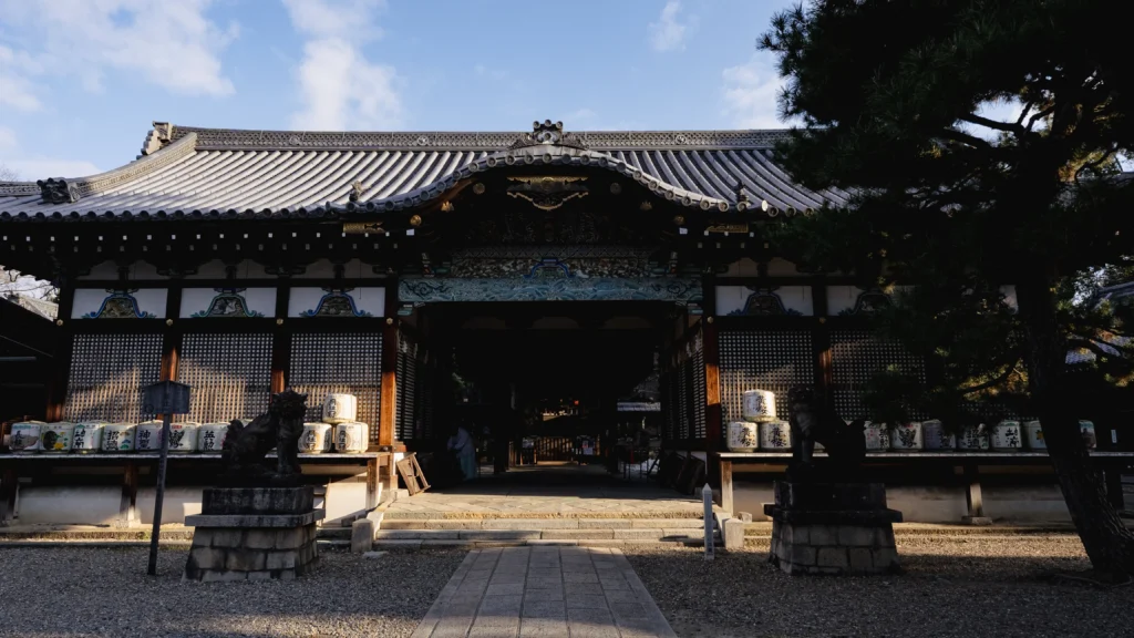 The ornate main hall of Gokonomiya Shrine in Fushimi, with offerings of sake barrels displayed prominently.