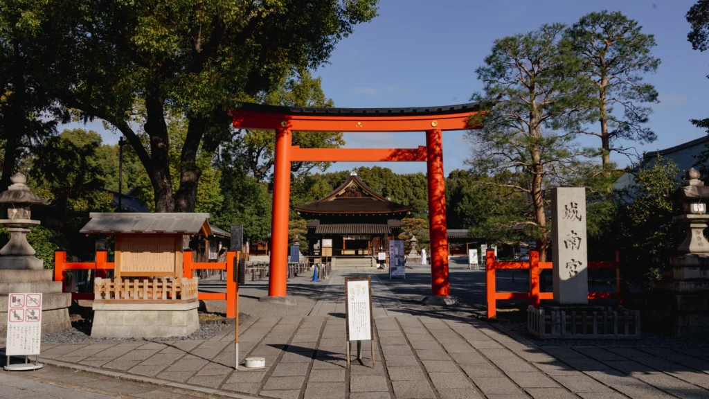 The grand vermilion torii gate at the entrance of Jonangu Shrine in Kyoto, with the stone monument bearing the shrine's name visible on the right.