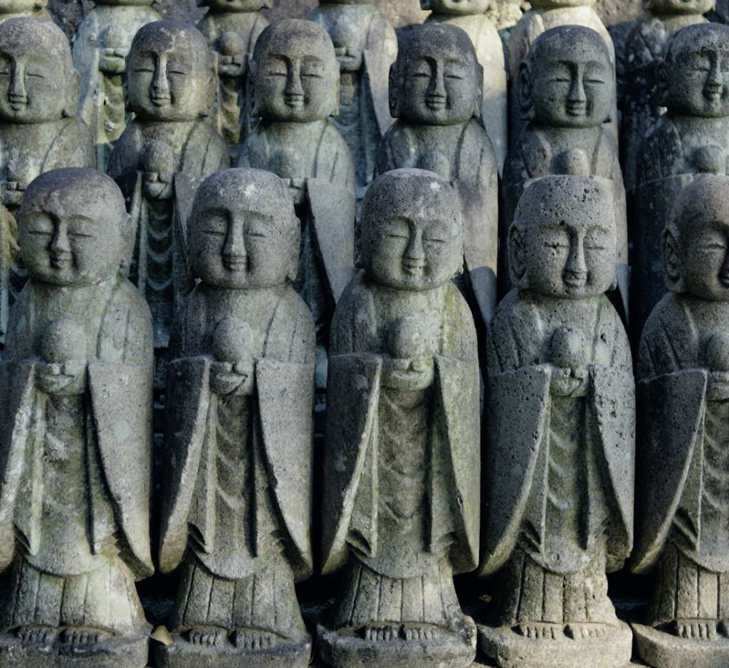 Rows of small stone Jizo statues with gentle smiling faces at Hasedera temple in Kamakura.