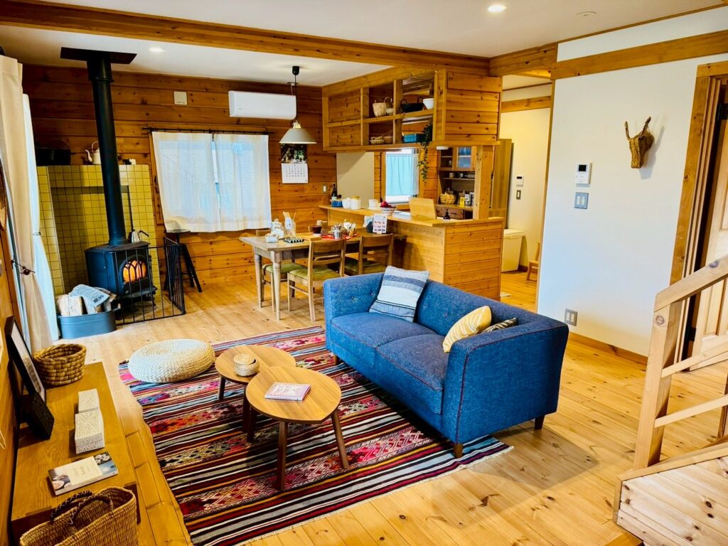 The inviting doma (earthen floor) space inside a BESS model home, featuring a wood-burning stove and rustic log board games.