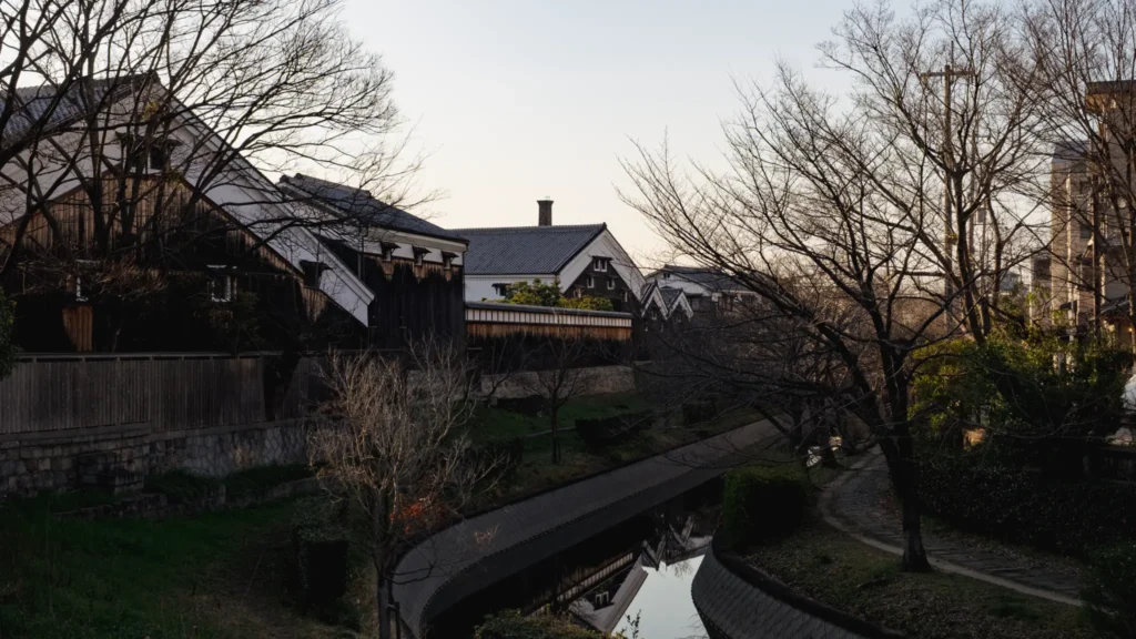 Traditional sake breweries with white walls and dark wood lining the Horikawa River in Fushimi, Kyoto.