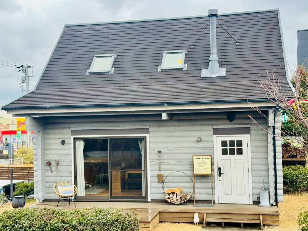 A close-up of a crackling wood-burning stove at BESS Kumamoto, with BESS-branded heat-resistant gloves nearby.