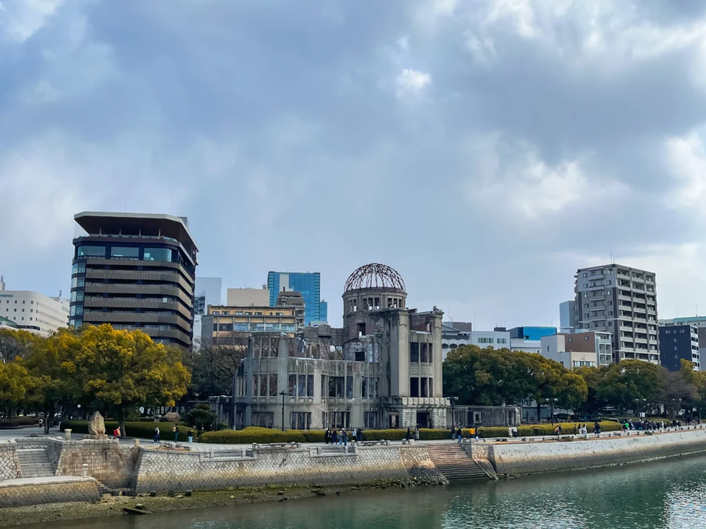 The Atomic Bomb Dome seen across the Motoyasu River, surrounded by modern Hiroshima