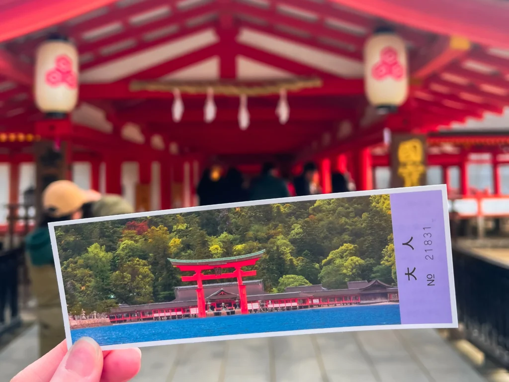 Itsukushima Shrine admission ticket with the shrine's white lanterns in background