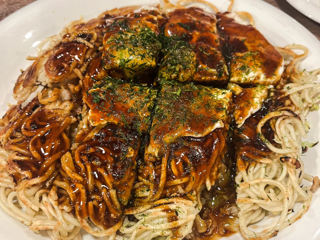 Hiroshima-style okonomiyaki at Mitchan, cut to reveal the layered cabbage, pork, and noodle interior