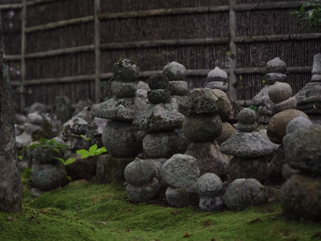 Stone Buddha statues and gorinto stupas packed tightly together on mossy ground
