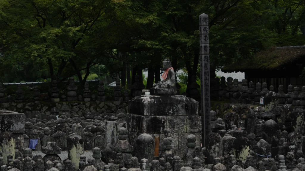 Moss-covered weathered stone Buddhas near bamboo fence at Adashino Nenbutsuji