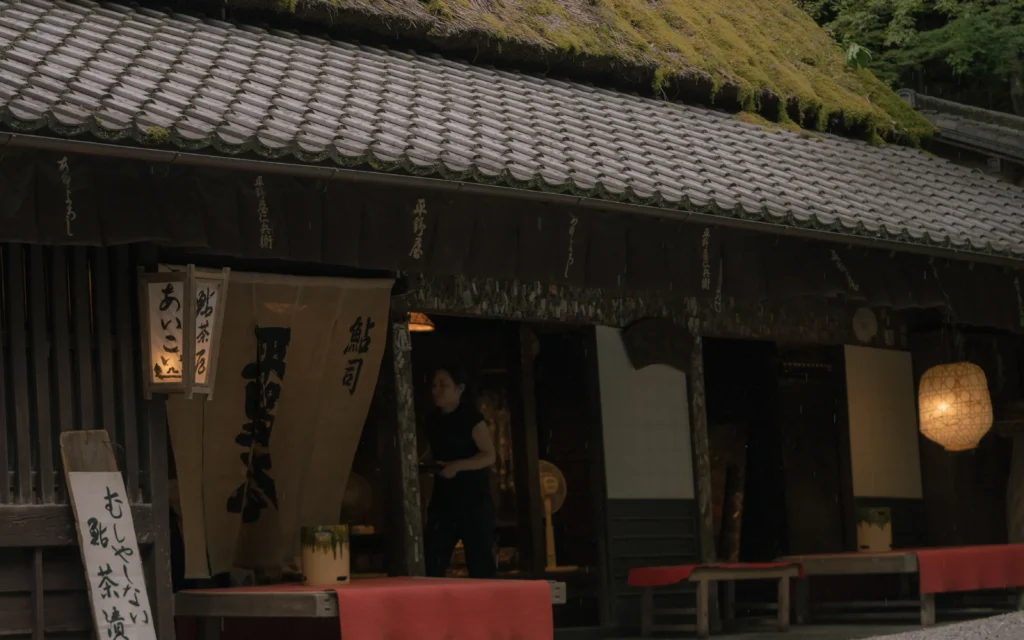 Interior entrance of a traditional tea house showing a wooden shop front with hanging "鮎茶屋" (ayu tea house) sign