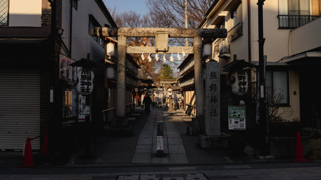 Stone torii gate at the entrance of Kawagoe Kumano Shrine with the approach path leading to the main hall in warm evening light