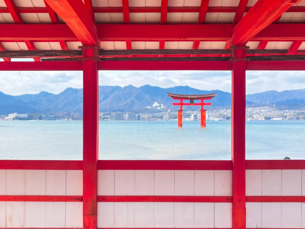 The floating torii gate framed through Itsukushima Shrine's vermillion corridor