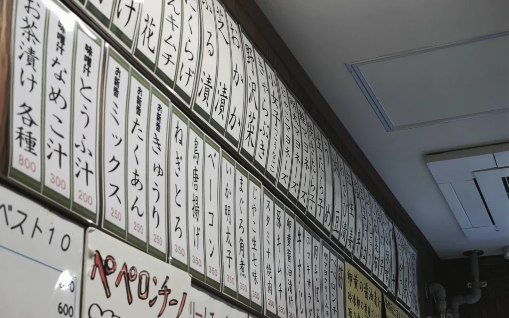 Interior wall of Onigiri Bongo covered in handwritten Japanese menu cards listing 50+ fillings