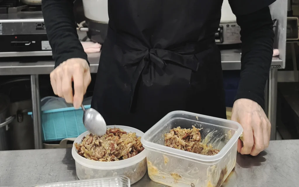 Chef scooping homemade onigiri fillings from plastic containers at Onigiri Bongo prep counter