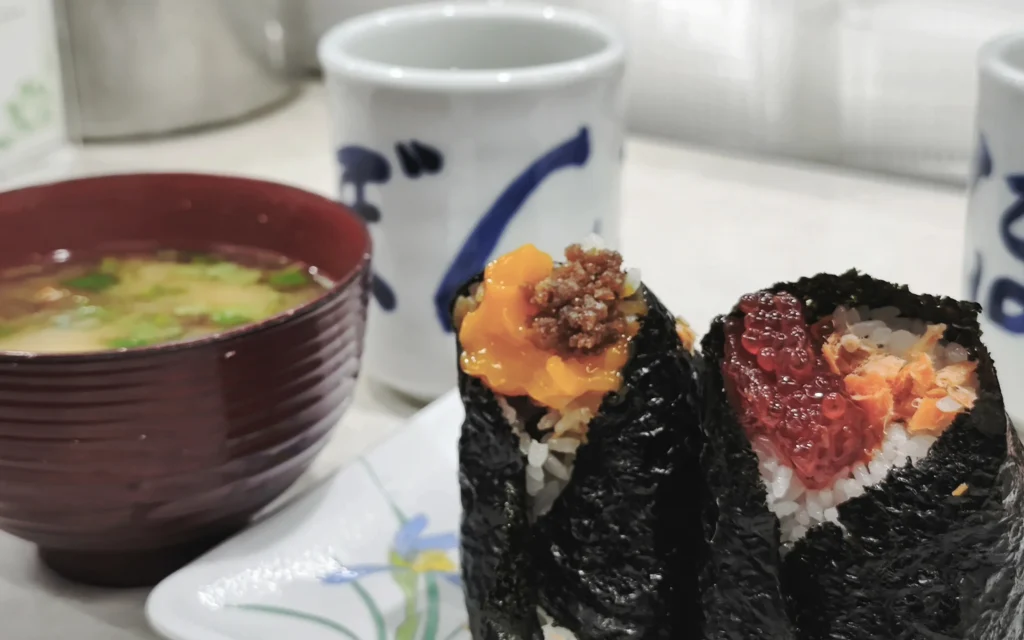 Two Onigiri Bongo onigiri with soy-cured egg yolk soboro and sujiko salmon roe fillings with miso soup