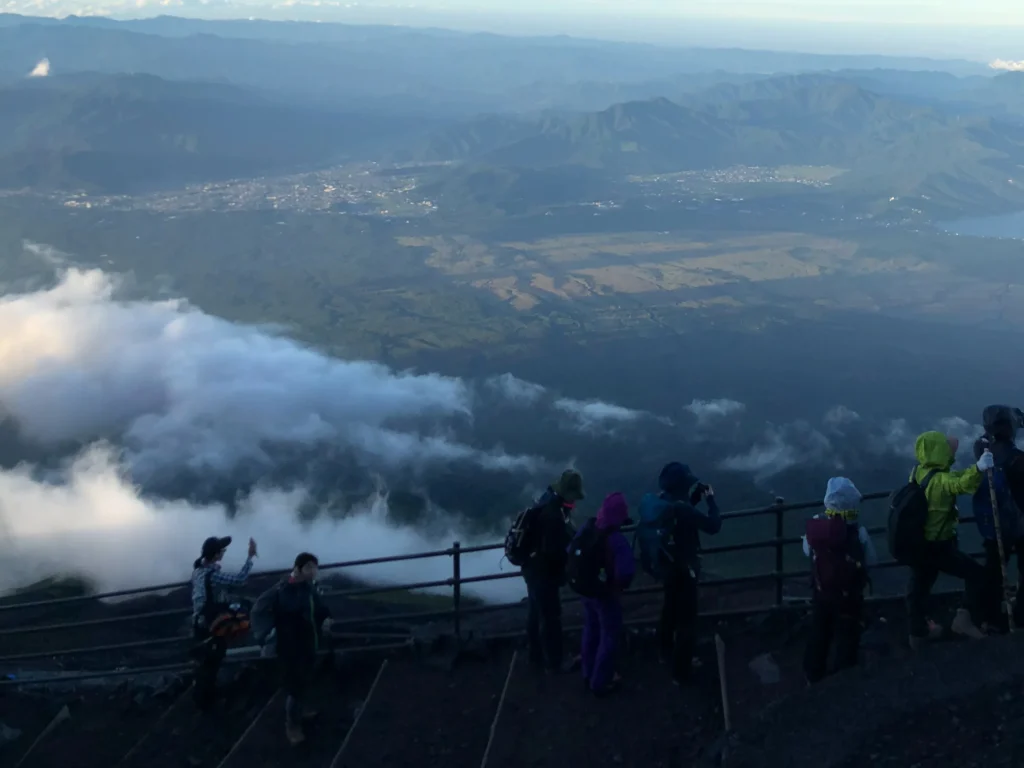 Climbers at mountain hut viewpoint railing looking down at clouds