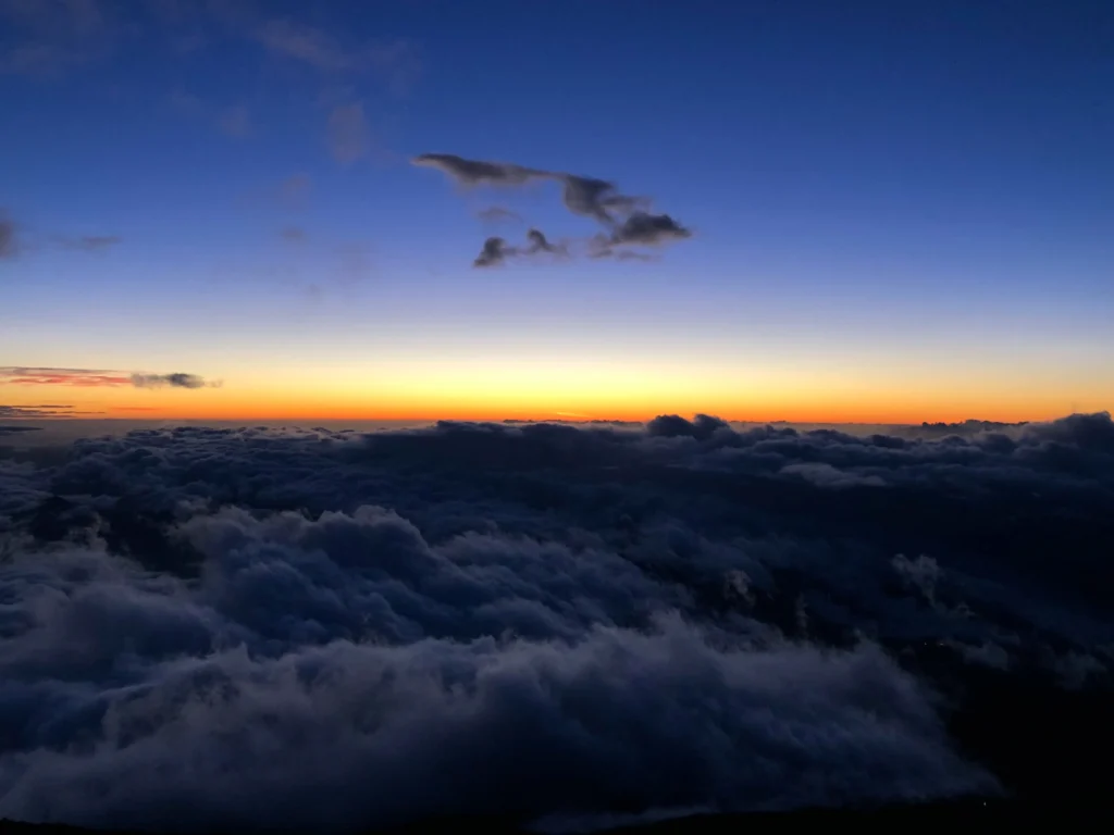 Dawn breaking with blue and orange gradient above a vast cloud sea