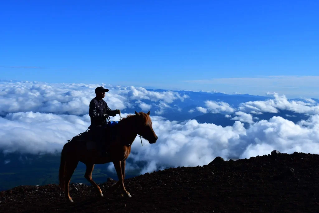 Silhouette of horse and rider against cloud sea on Mt. Fuji volcanic slopes