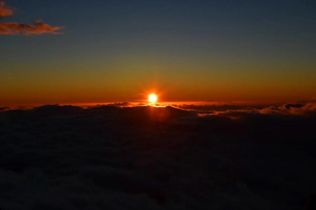 Deep orange sunset with sun touching the cloud horizon