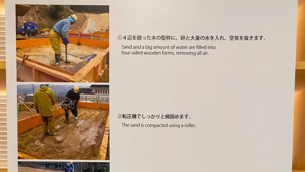Museum panel explaining the sand sculpture production process — filling wooden forms with sand and water