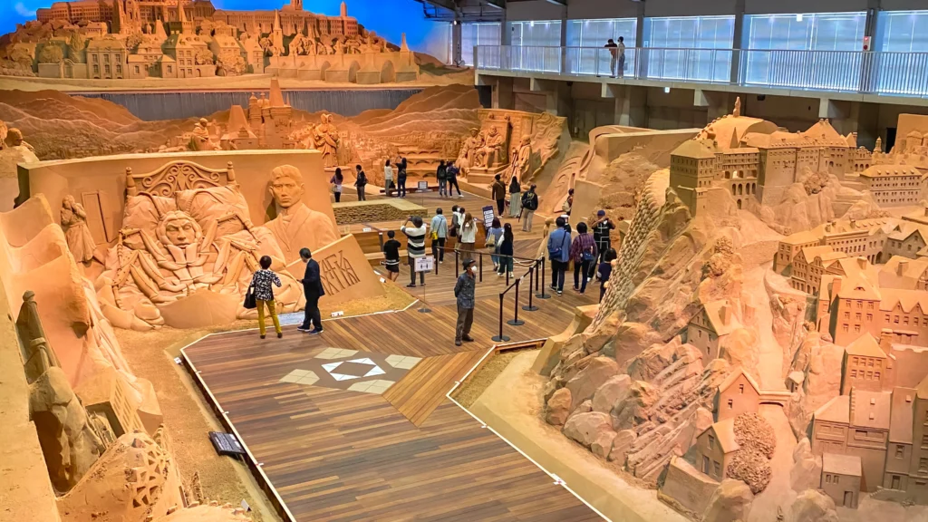 Elevated view of the entire Sand Museum exhibition hall showing monumental sand sculptures on both sides of the central walkway